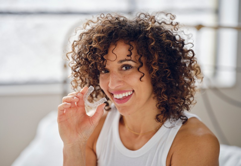 Smiling woman holding Candid Clear Aligners in Millersburg, OH for straighter, healthier teeth