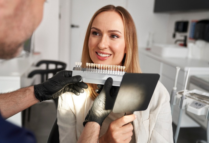 A dental expert assists a patient with veneer shade for composite vs porcelain in Millersburg, OH
