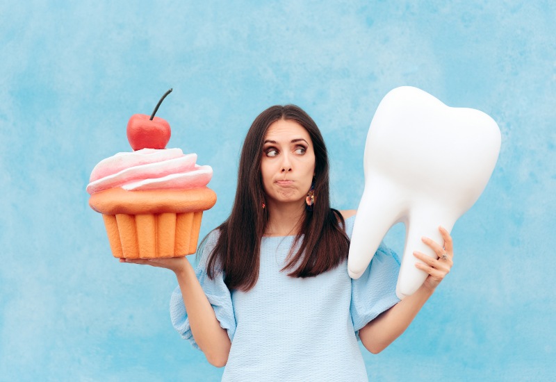 A woman compares a cupcake and a tooth symbolizing the effects on oral health in Millersburg, OH