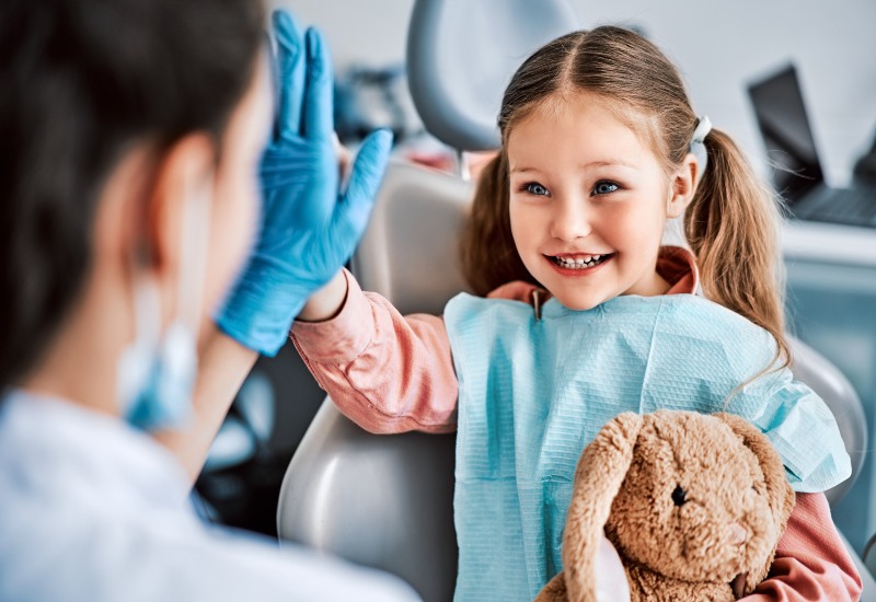 A dentist and a happy child share a high-five during early orthodontic evaluation in Millersburg, OH