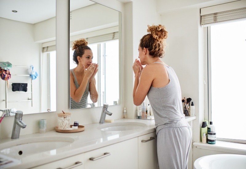 A woman focusing on oral hygiene in a bathroom, checking for bad breath in Millersburg, OH