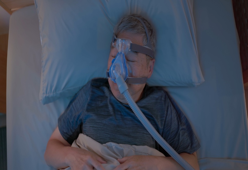 An elderly adult using a CPAP mask and tubing for sleep apnea treatment in Millersburg, OH
